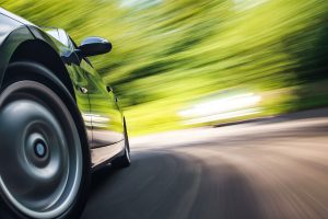 Vehicle driving on a road. Blur in photo implies car is speeding.
